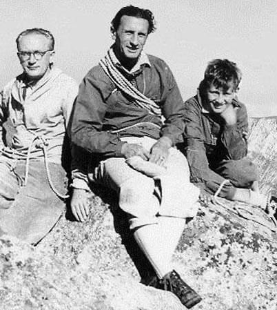 Three mountaineers with hemp ropes and 1930s mountain clothing sitting on a rocky summit